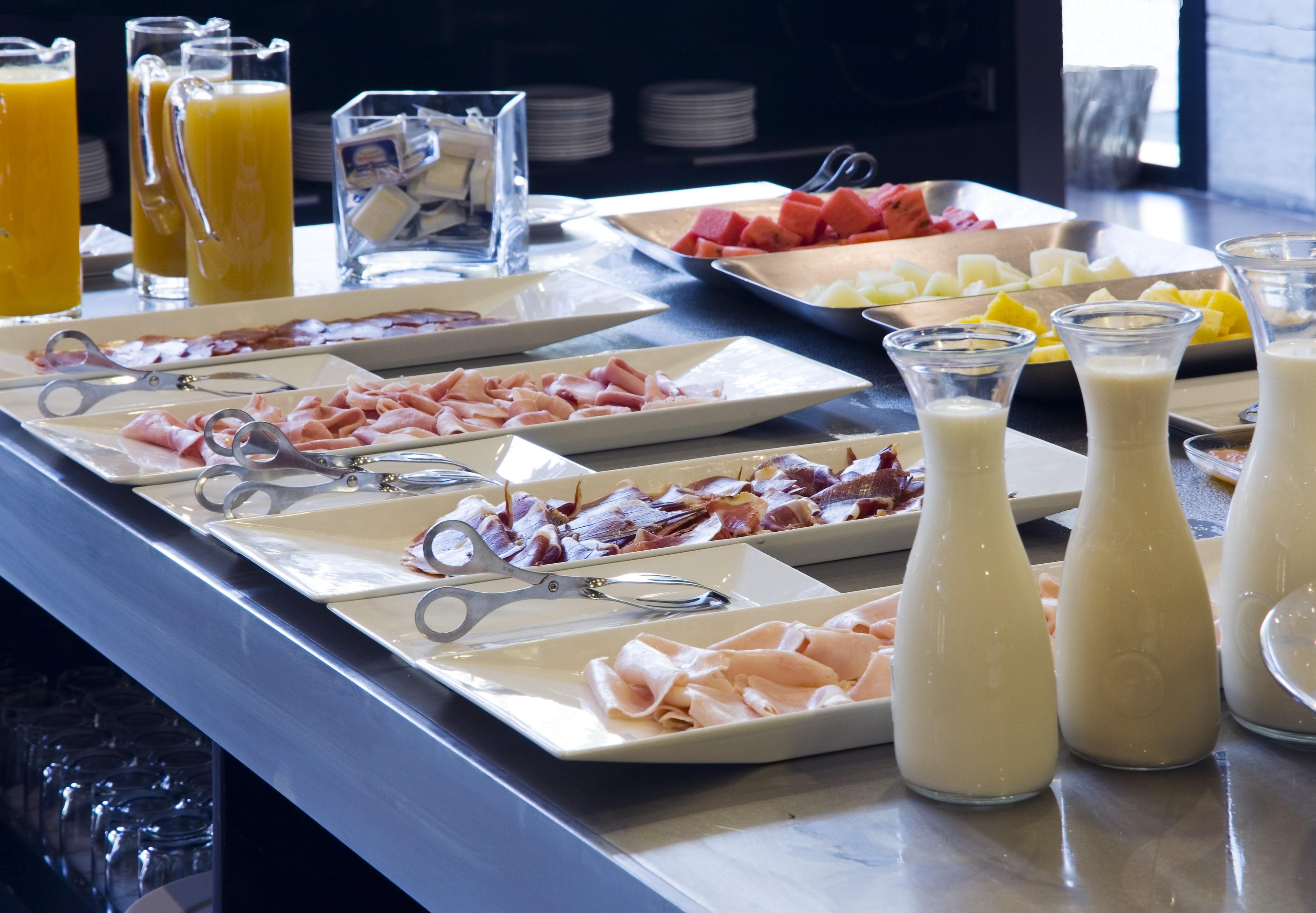 Eurostars Palace Кордоба Екстериор снимка The photo displays a buffet area with various food items arranged on a countertop. There are multiple plates featuring an assortment of sliced meats, likely including ham and possibly turkey or chicken. Additionally, two glass pitchers are filled wit