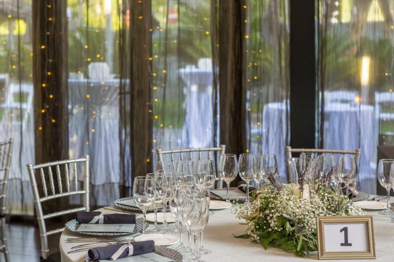 Eurostars Palace Кордоба Екстериор снимка The photo shows a beautifully set dining table in an elegant event space. The table is round, covered with a white tablecloth, and adorned with a centerpiece of greenery and flowers. There are several wine glasses and water glasses arranged neatly on