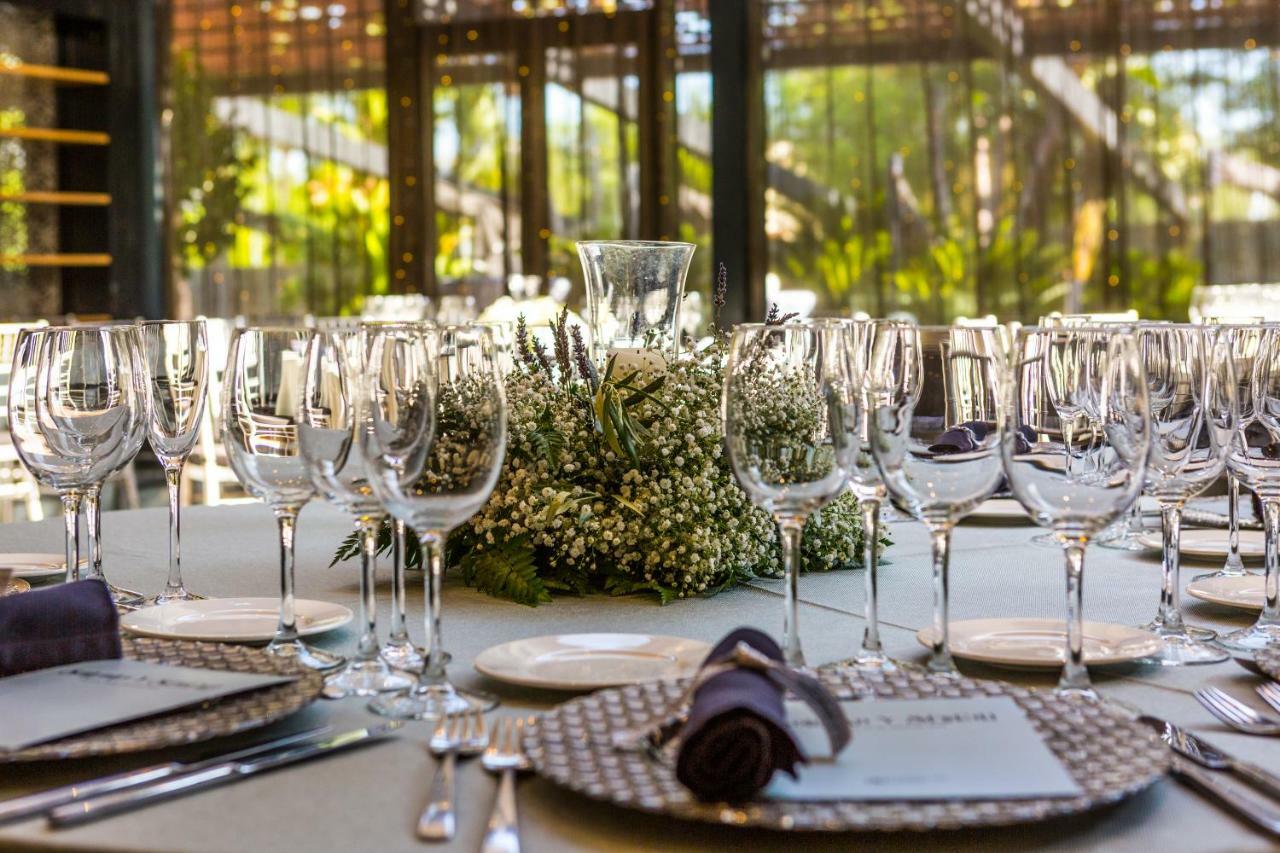 Eurostars Palace Кордоба Екстериор снимка The photo displays an elegantly set dining table arranged for a formal event. The table is adorned with a centerpiece made of white flowers and greenery, surrounded by numerous glassware, including wine glasses and water goblets. Each place setting i